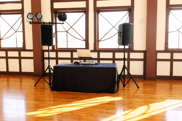 Corporate event DJ setup with professional sound system, lighting, and DJ equipment in a bright indoor venue.