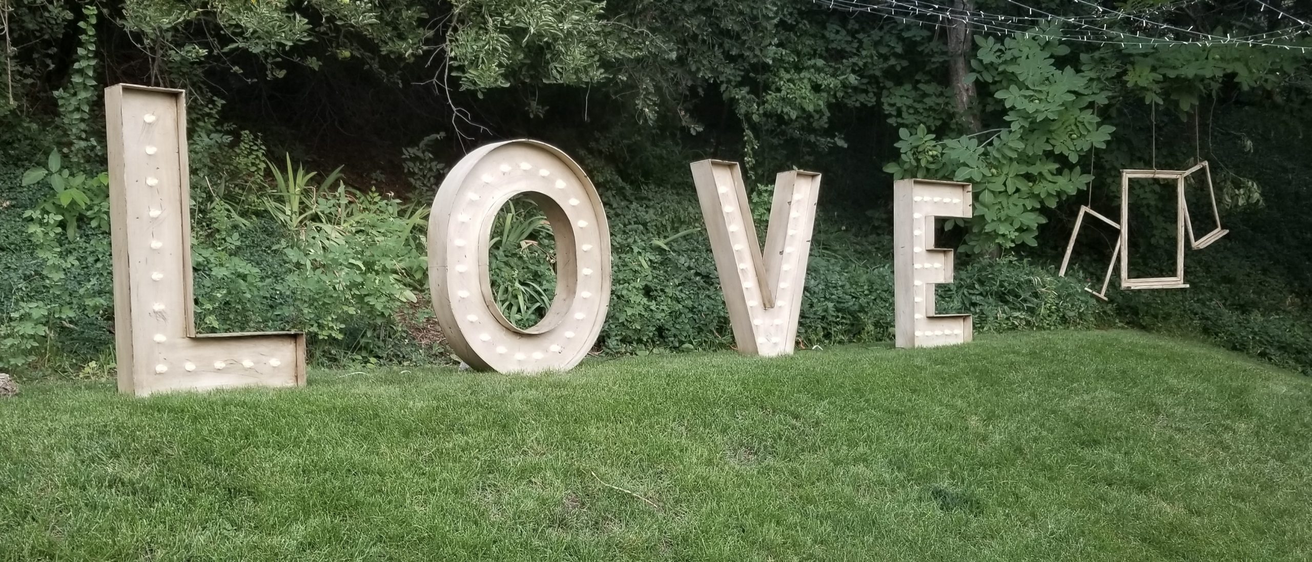 Large illuminated “LOVE” letters displayed outdoors at a wedding venue.